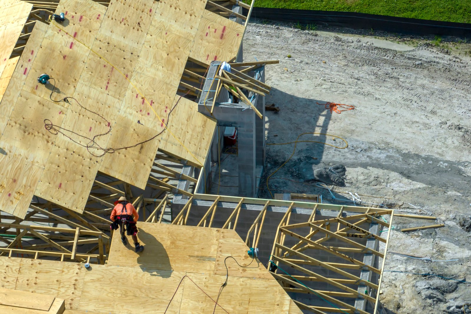 Professional builders working on roof construction of unfinished suburban home with wooden frame structure in Florida rural area. Concept of housing development in Conroe Texas